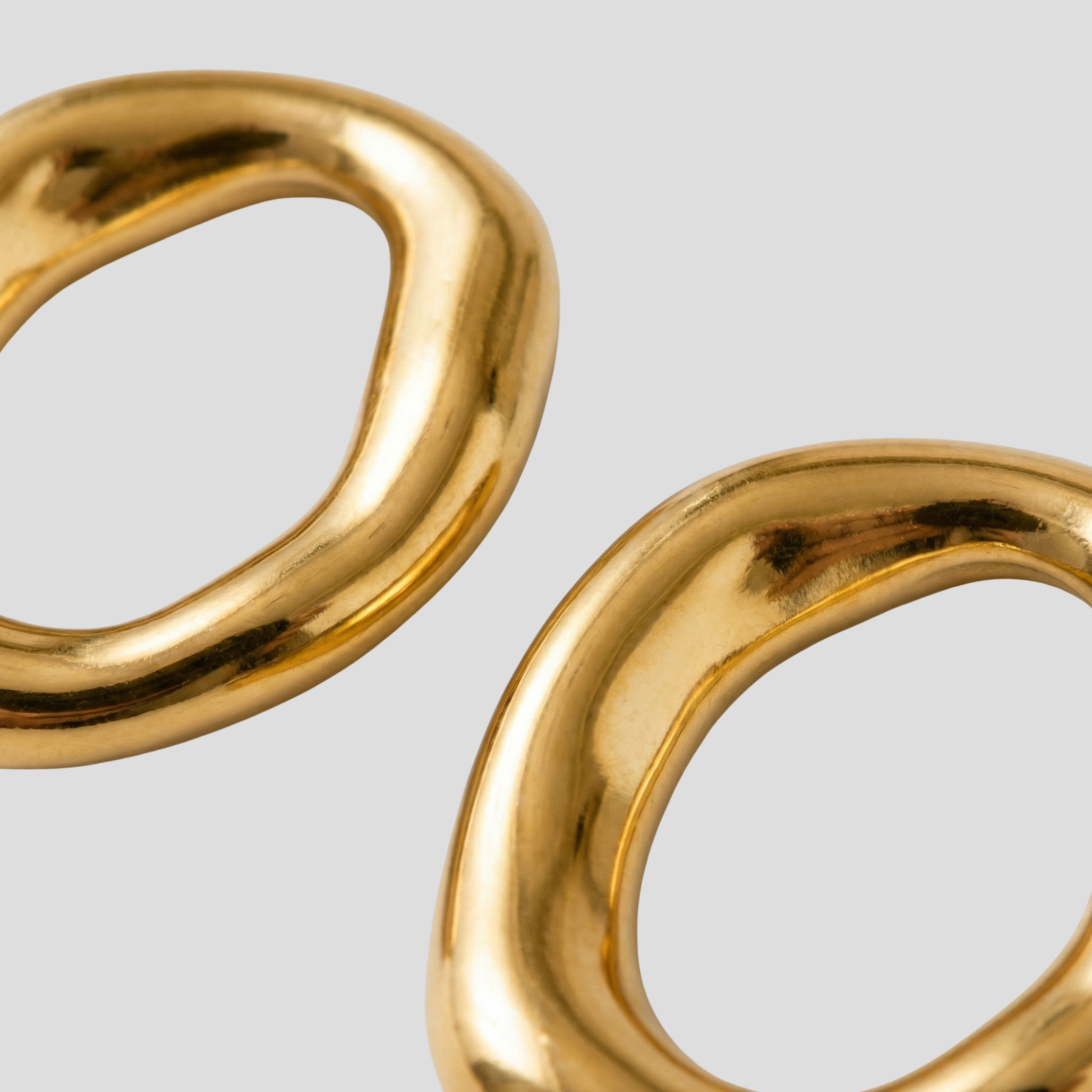 Gold-tone sculptural oval drop earrings with a smooth polished outline