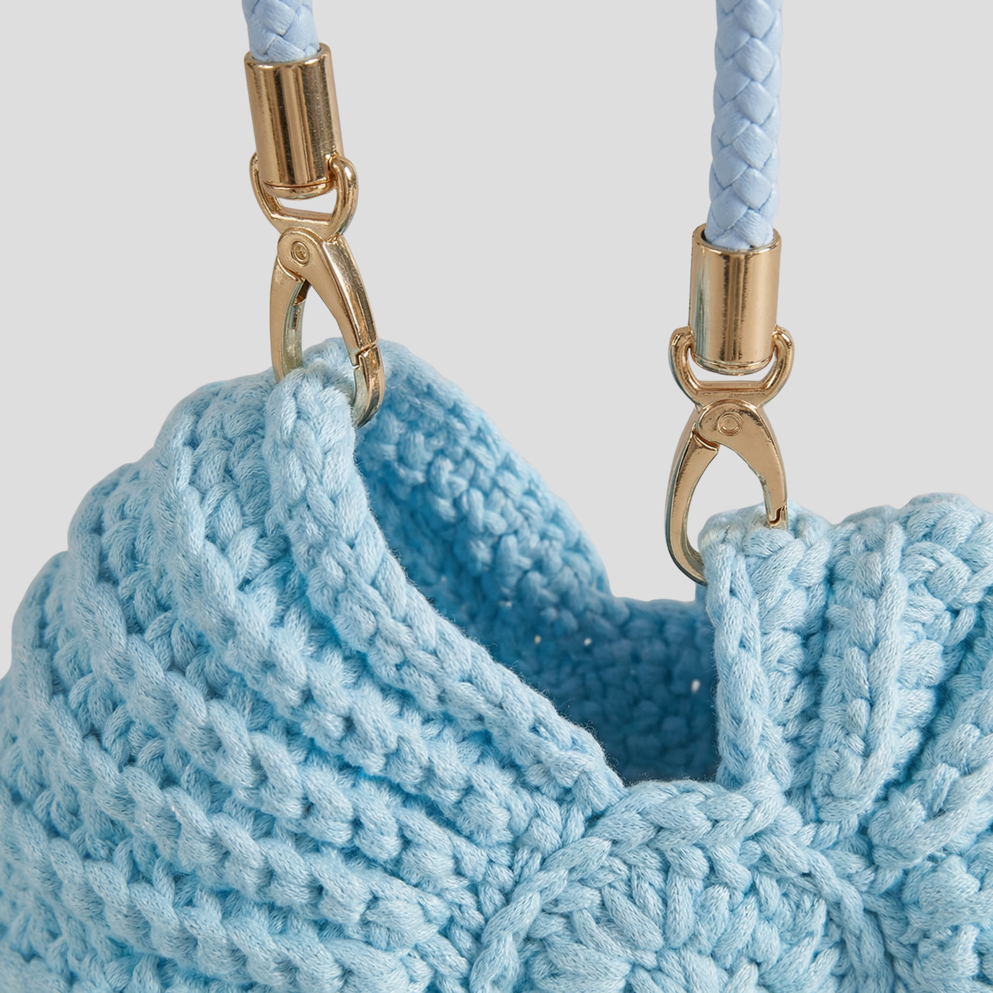 Conch-shaped woven handbag with sculptural silhouette, shown in blue, black, and white