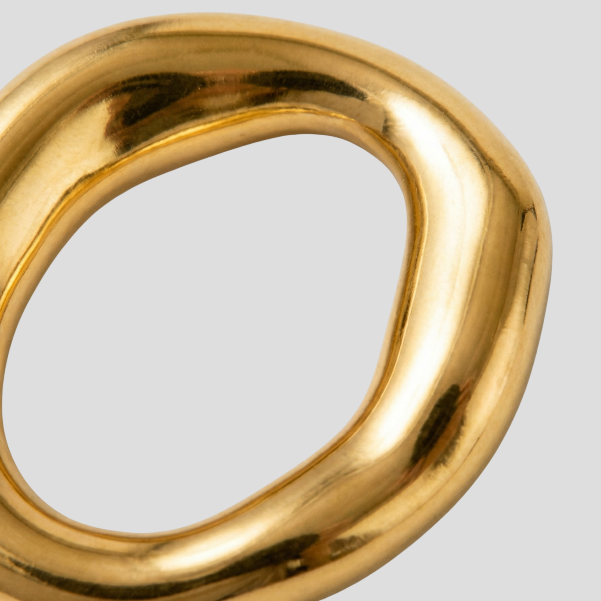 Gold-tone sculptural oval drop earrings with a smooth polished outline