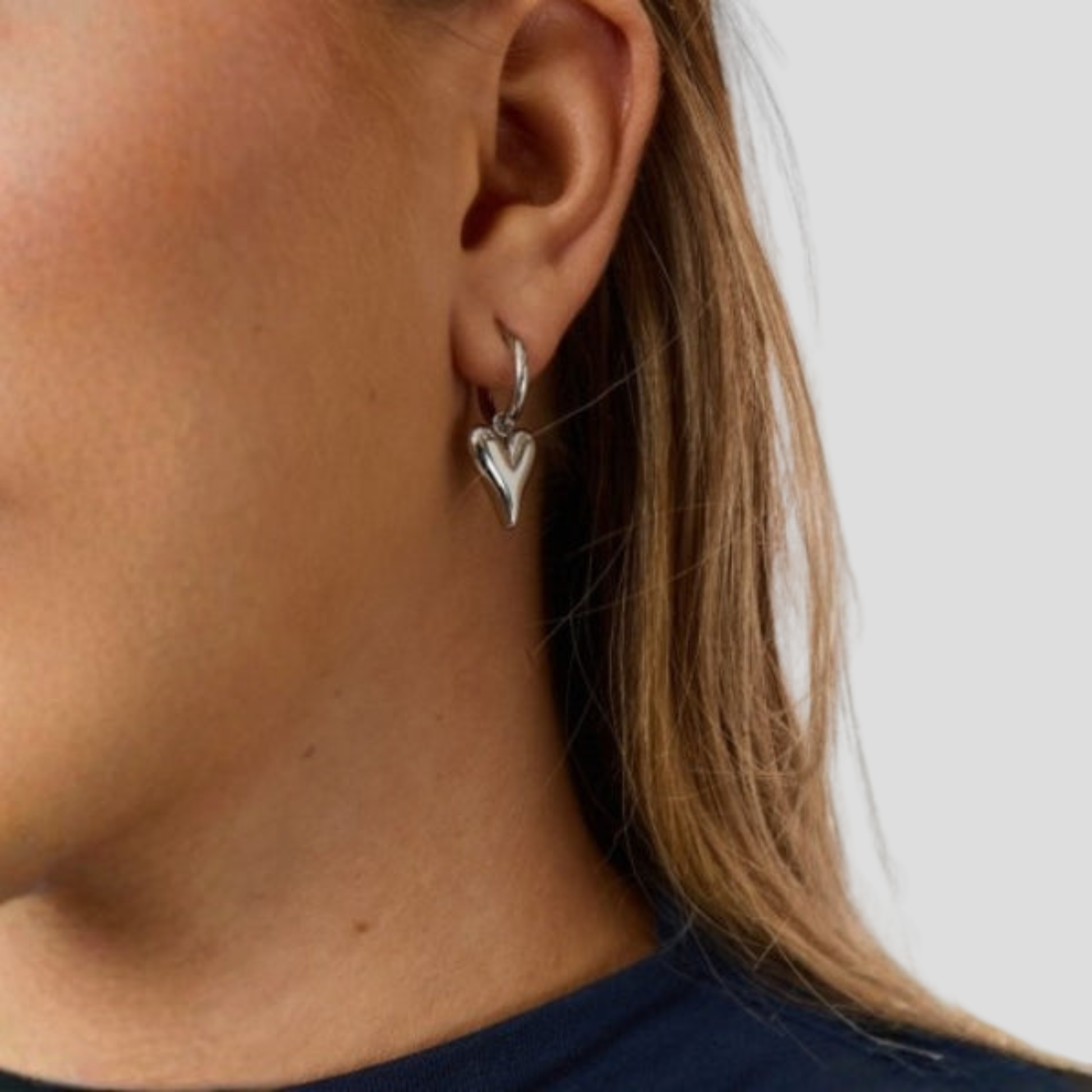 Sculpted heart-shaped earrings with a polished silver finish for women