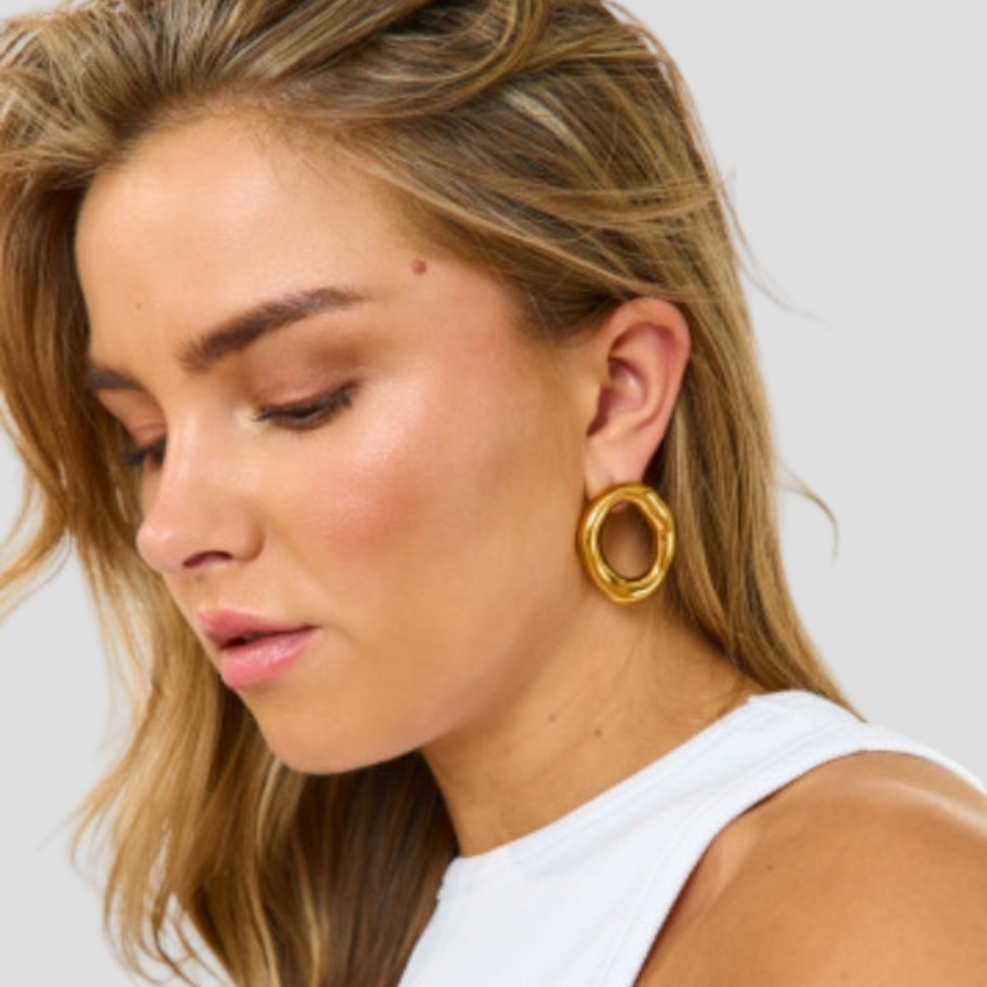 Gold-tone sculptural oval drop earrings with a smooth polished outline