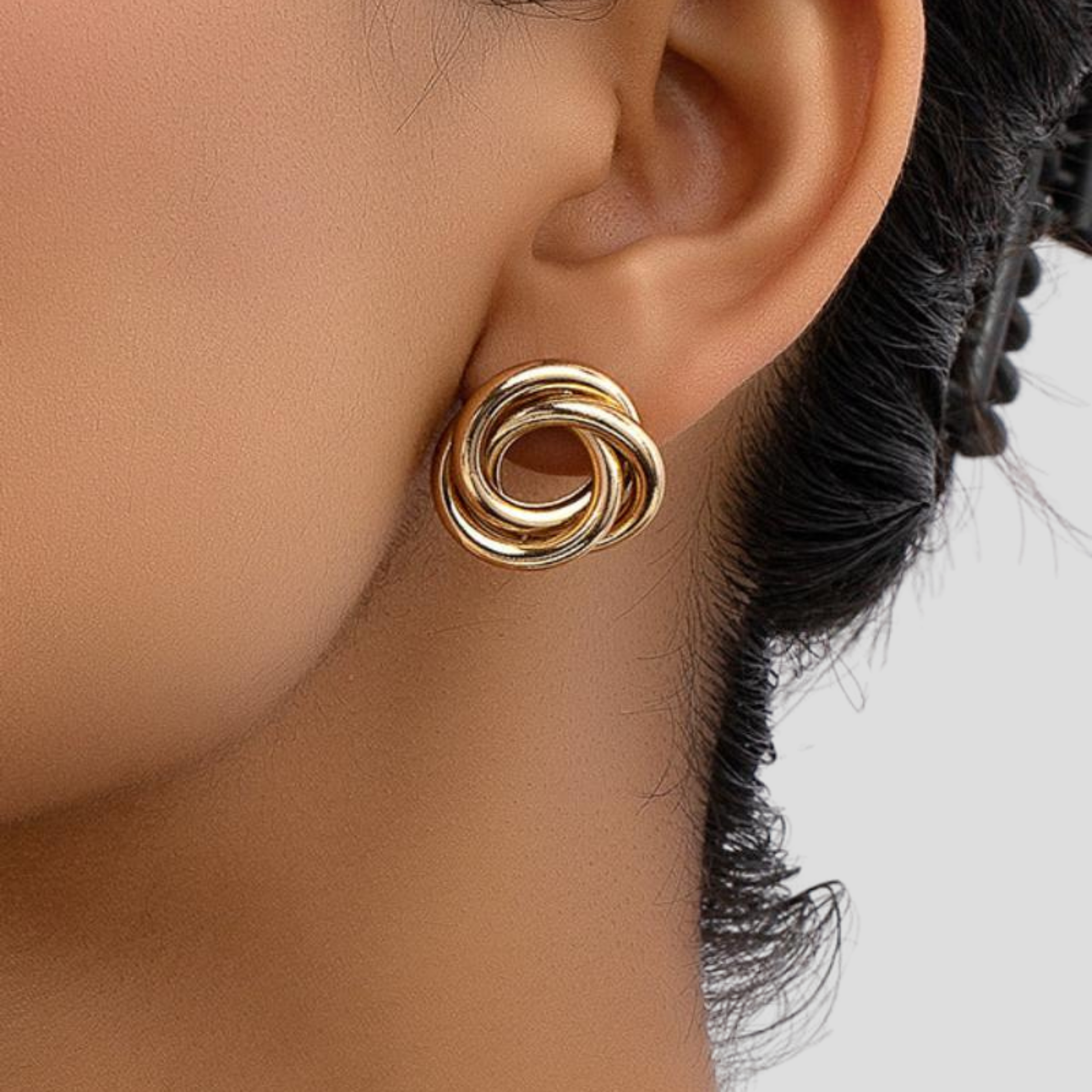 Gold-tone interwoven knot stud earrings with a polished outline for everyday wear